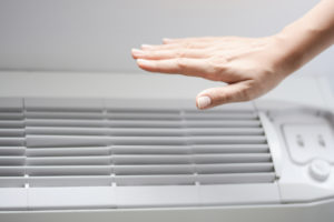 ductless mini split with hand on top to feel the heat or air coming out