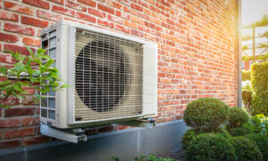 Air conditioning heat pump outdoor unit against brick wall.