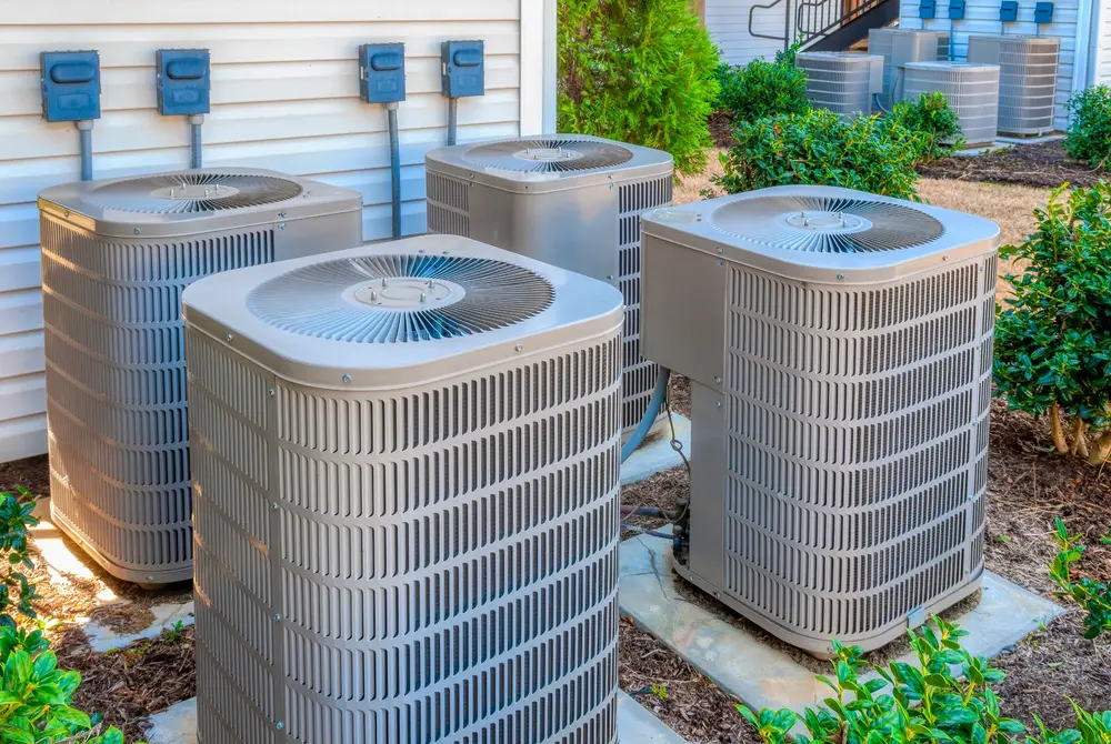 4 AC condenser unites in a residential backyard