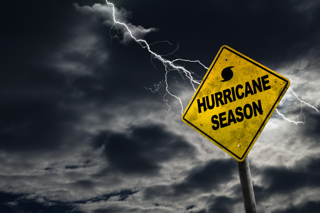 Lightning in a stormy sky with a yellow road sign that reads "hurricane season)