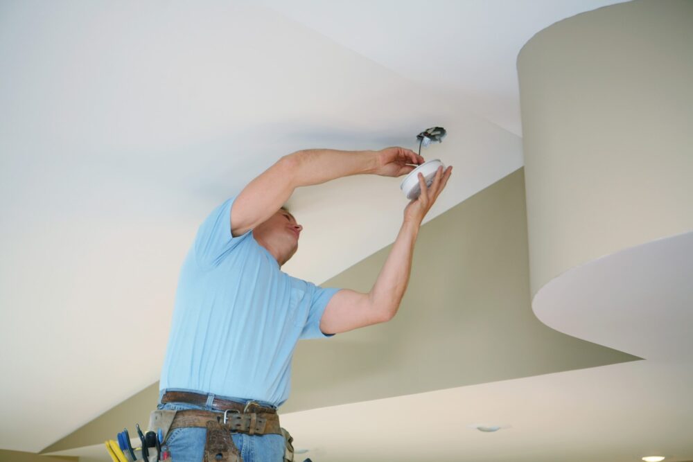 Technician installing smoke detector in a home